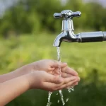 boy-washes-his-hand-under-faucet-garden-72492444